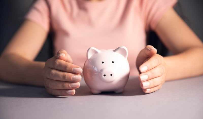Women holding a piggy bank and coin